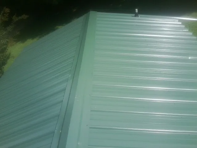New green metal panels meeting at the ridge of a roof — Flat Roof Repair work by our crew in Salix