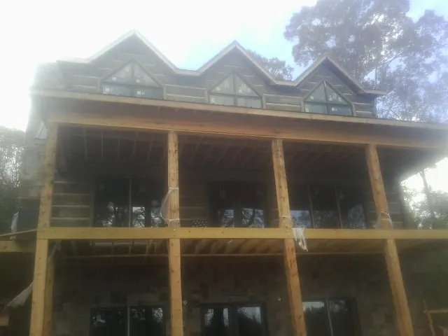 Dormers and porch framing on a large log home under construction — Roof Coating work by our crew in Salix