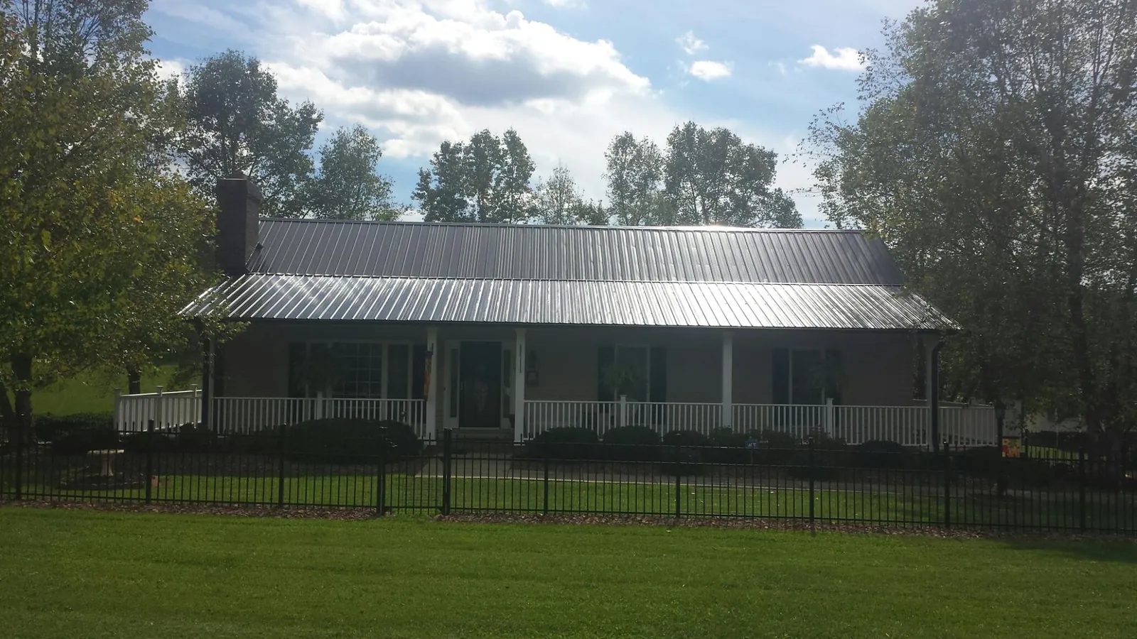 Gray metal roof on a brick ranch with a full width front porch — Gutter Guard Installation work by our crew in Salix