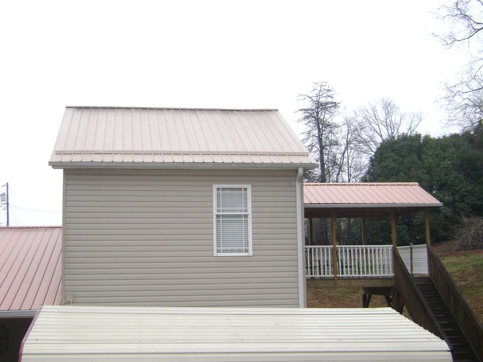 Tan metal roofs on a two story addition and attached porch, from a Roof Replacement job in Salix