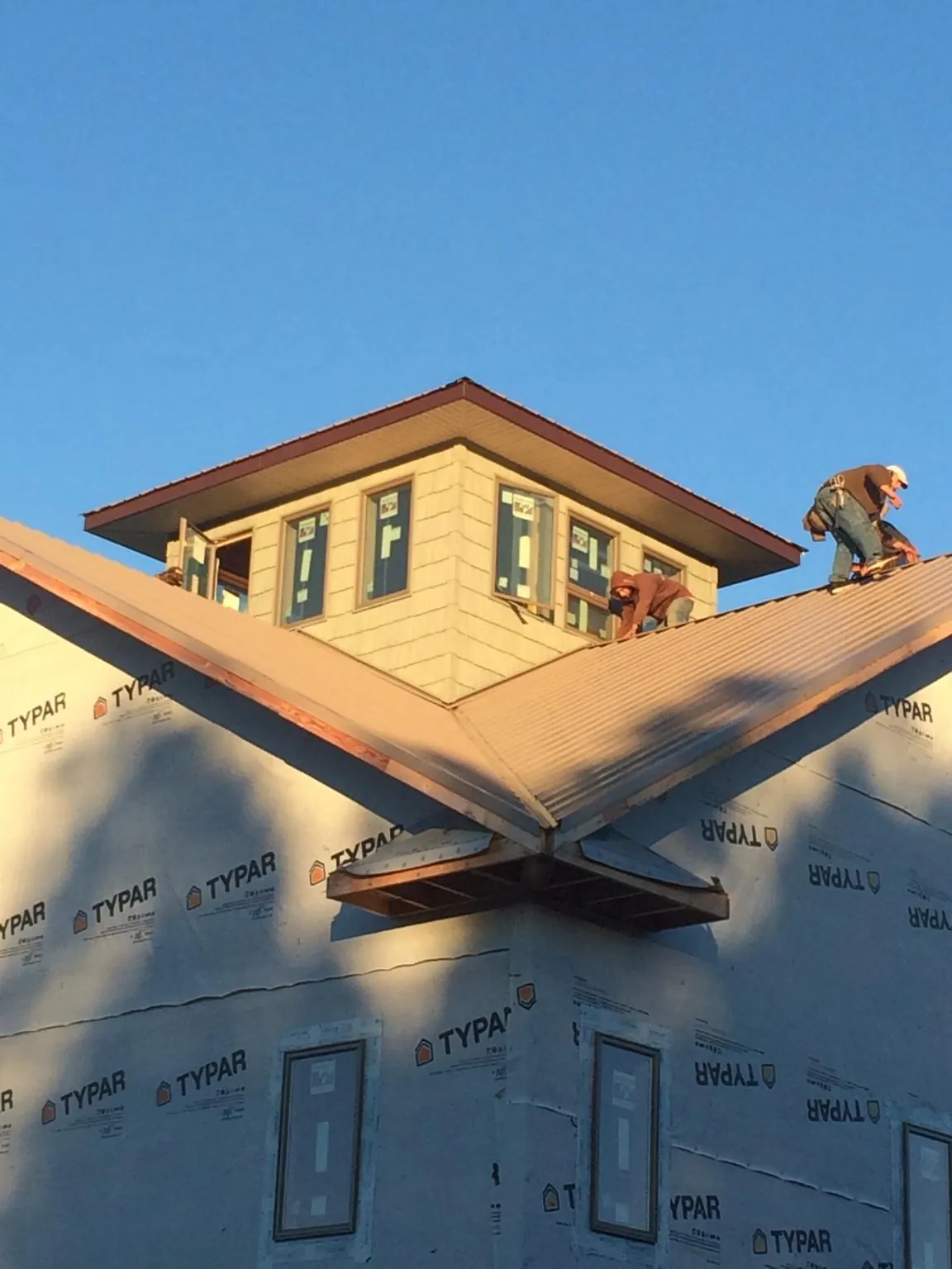 Roofers working around a rooftop cupola on a new metal roof at sunset — Roof Waterproofing in Salix by Roofing Brothers
